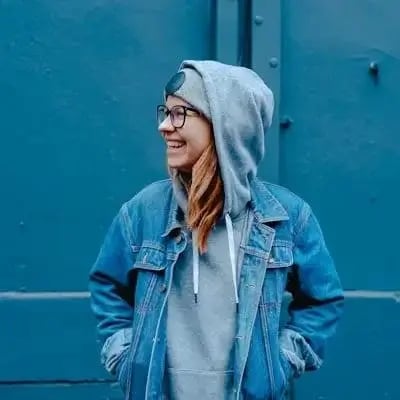 Portrait of a woman in a denim jacket against a blue wall